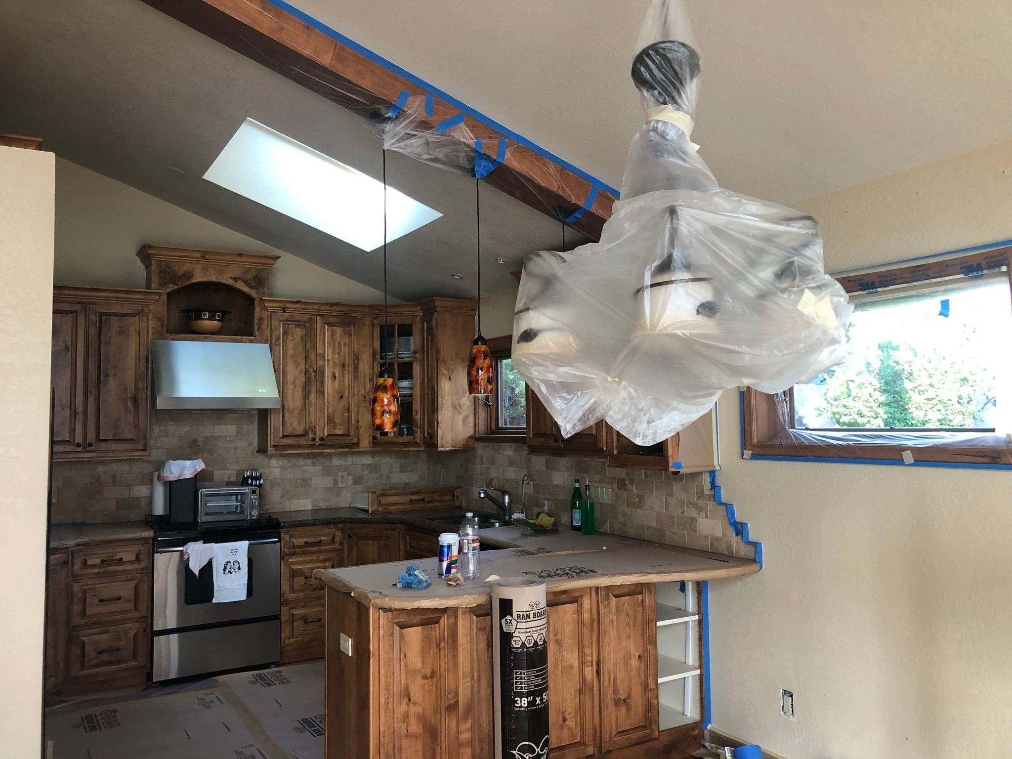 Kitchen & overhead light covered with plastic in anticipation of drywall remodel.
